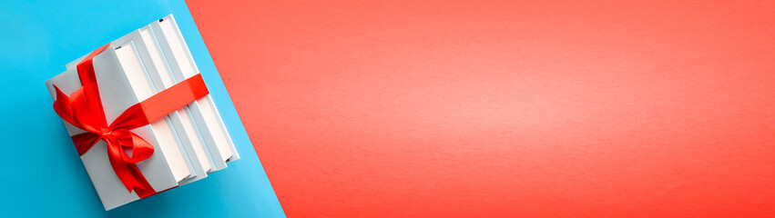 Stack of books in a gift ribbon on a colored background with copy space web banner: concept of...