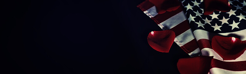 American flag and rose flower on the table. Symbol of the United States of America and red petals. Patriotism and memory.