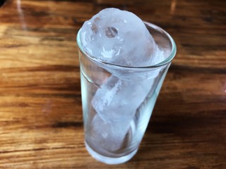 Ice in glass on wooden table.