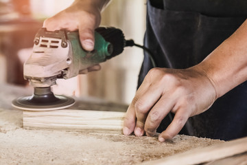 Carpentry is using an electric sander, to smoothen the wood texture. Small business woodworking
