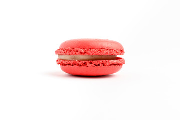 Side view of one sweet vivid red strawberries French macaron isolated on white background, tasty French dessert on a table