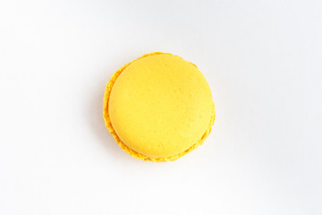 Top view of one sweet vivid yellow lemon French macaron isolated on white background, tasty French dessert on a table