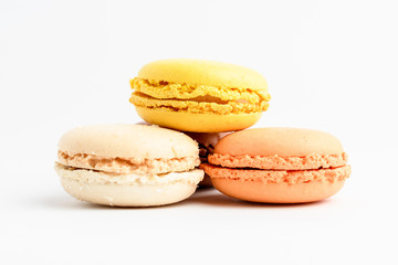 Side view of three sweet lemon, orange and vanilla French macaron isolated on white background,