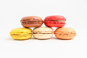 Five sweet French macarons with different aromas, isolated on white, flavours of strawberries, lemon, caramel, vanilla, orange and chocolate, tasty dessert in pastel colors on a table