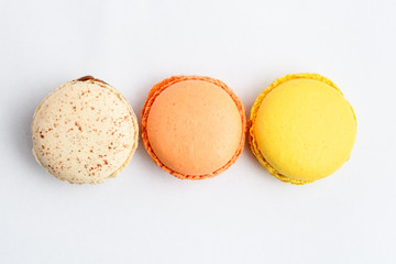 Top view of row of three sweet French macarons with different aromas, isolated on white, flavours...