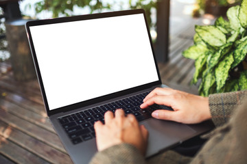 Mockup image of a woman using and typing on laptop computer with blank white desktop screen in the outdoors