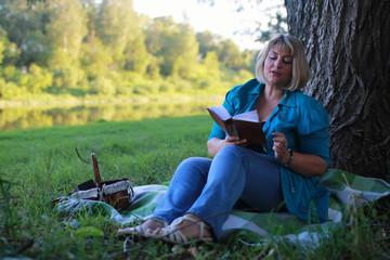Naklejka na ściany i meble woman in park with book on the grass