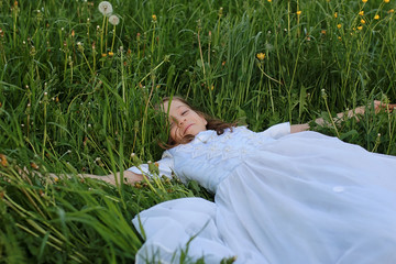 Teen blowing seeds from a dandelion flower in a spring park