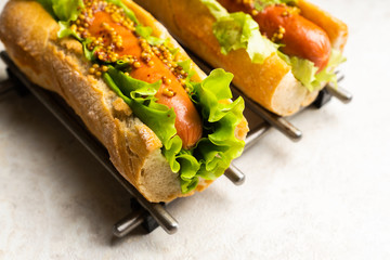 Tasty fresh hot dogs with grilled sausage, french mystard and fresh salad leaves on the rustic...