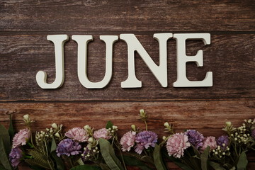 June alphabet letters with flower decoration on wooden background