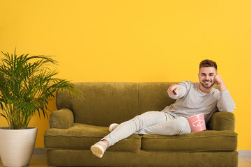 Young man watching movie while sitting on sofa at home