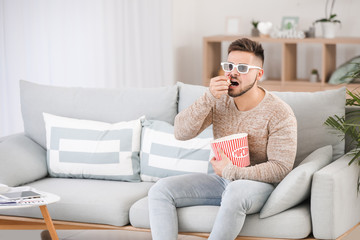 Young man watching movie while sitting on sofa at home