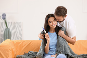 Happy young couple with pregnancy test at home