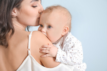 Cute baby with mother on light background