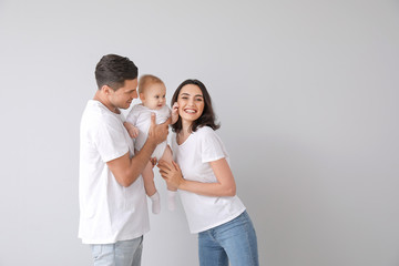 Cute baby with parents on light background