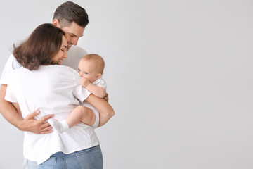 Cute baby with parents on light background