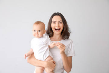 Cute baby with mother on light background
