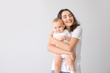 Cute baby with mother on light background