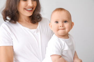 Cute baby with mother on light background
