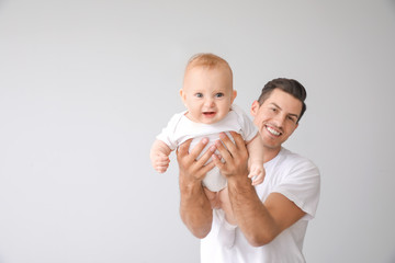Cute baby with father on light background