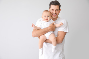 Cute baby with father on light background