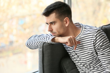 Obraz premium Depressed young man near window at home