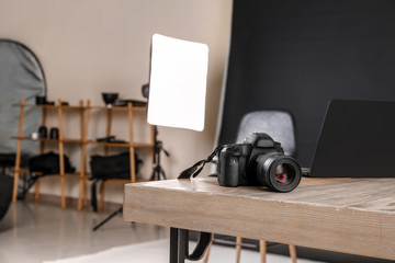 Modern camera on table in professional photo studio