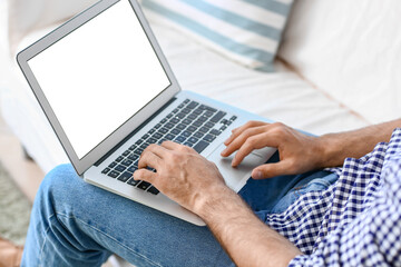 Handsome man working on laptop at home, closeup