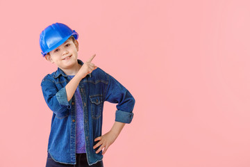 Cute little builder pointing at something on color background