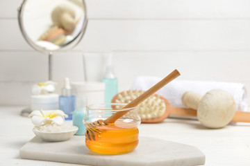 Jar with honey and spa items on table