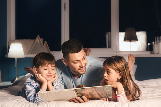 Father and his little children reading bedtime story at home