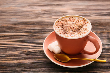 Cup of tasty cappuccino on wooden background