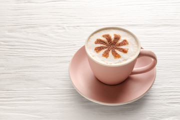Cup of tasty cappuccino on white wooden background