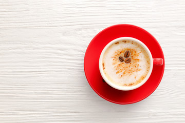 Cup of tasty cappuccino on white wooden background