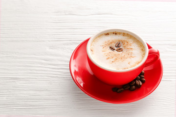 Cup of tasty cappuccino on white wooden background