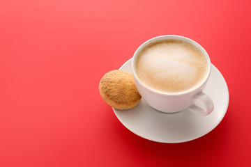 Cup of tasty cappuccino and cookie on color background