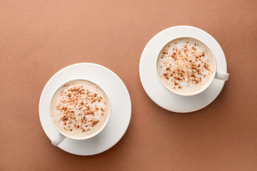 Cups of tasty cappuccino on color background