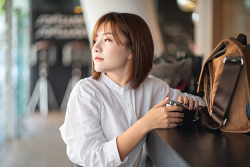 Young Asian woman model with retro film camera wearing a white shirt.