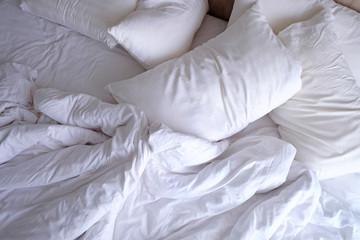 Obraz premium Top view unmade bed with white pillows, blanket and bedsheet