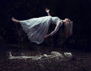 Levitation image of a woman rising from a skeleton on dead leaves - 328650461