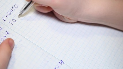 The child does school homework, solves arithmetic examples and writes them in a notebook. Affordable education concept.