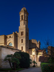 Obraz premium Duomo of Sassari the bell tower - low angle view of historic building against clear classical blue sky. Historic architecture with its pastel earth-colored natural stone walls