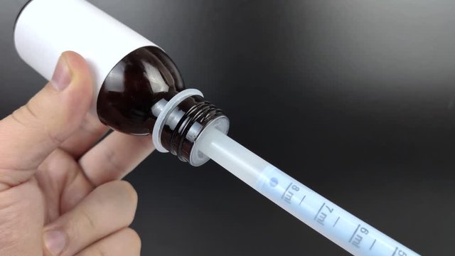 A liquid antipyretic is collected in a plastic syringe for oral use. Macro video of a fever medication.