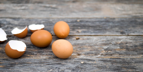 Eggs and egg shells placed on a wooden plate, leaving an empty space on the right.