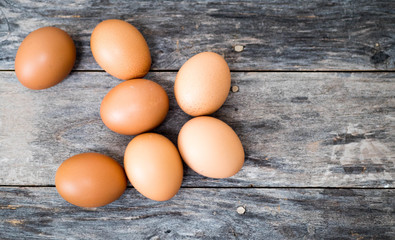 The chicken eggs are placed on the left, at a high angle, on a piece of wood, in a dark gray background.