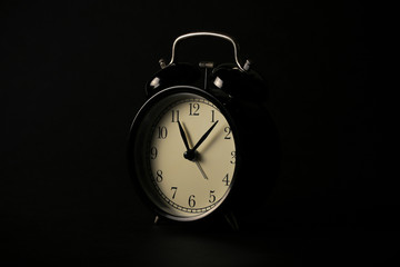 a black clock stands at night on a black background