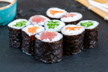 A selection of sushi rolls with salmon, tuna, cucumber and soy sauce dip.