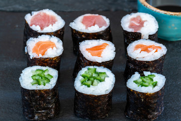 A selection of sushi rolls with salmon, tuna, cucumber and soy sauce dip.