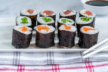 A selection of sushi rolls with salmon, tuna, cucumber and soy sauce dip.