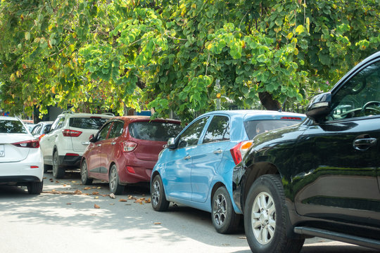 Parallel cars parking on street with green trees